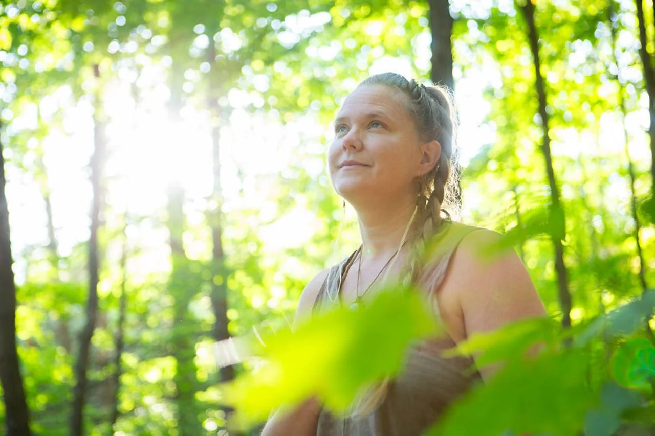 Tiina Kivinen in a sunlit forest.